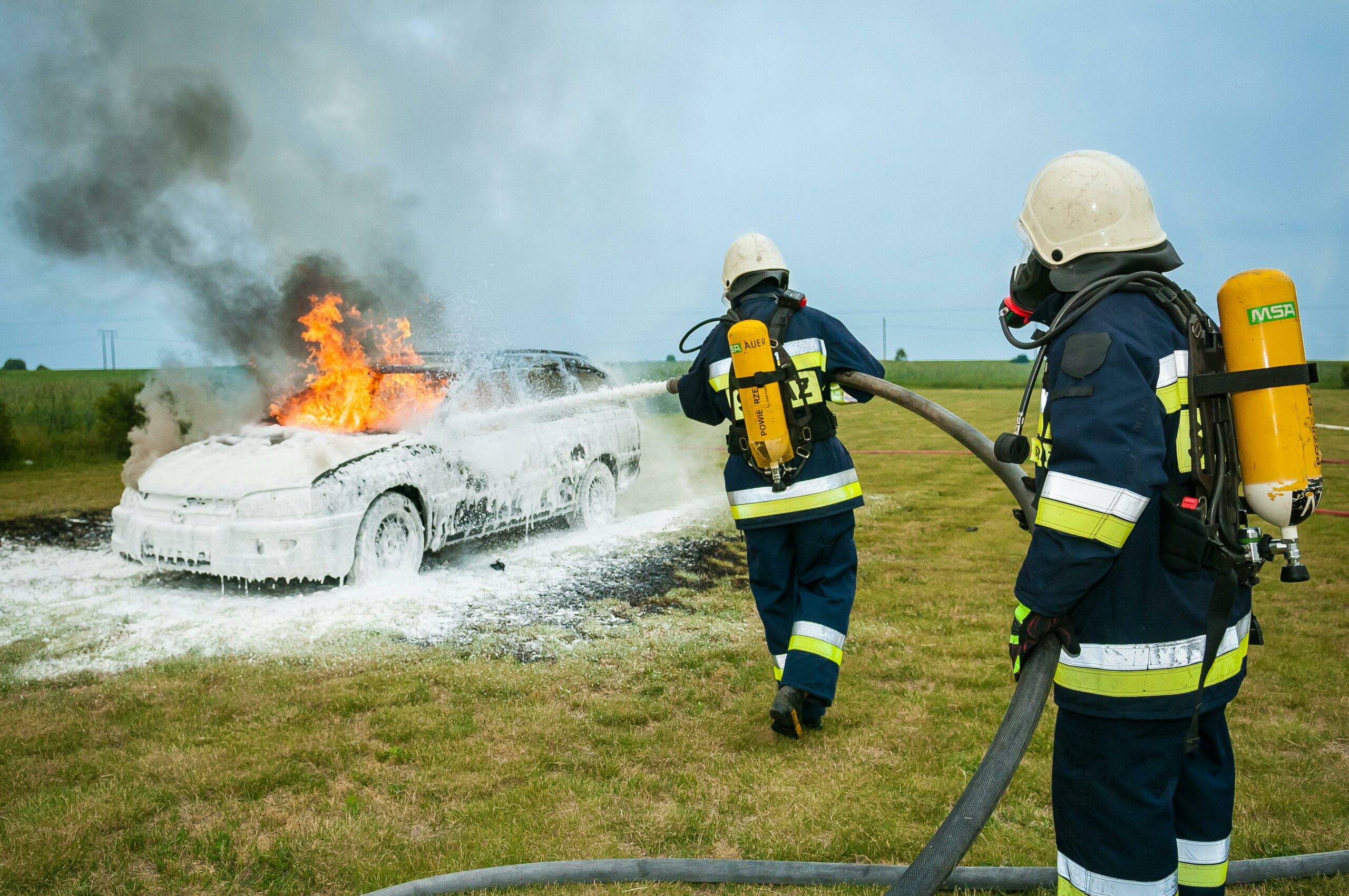 Zwei Feuerwehrmänner Sprühen Auf Brennendes Fahrzeug